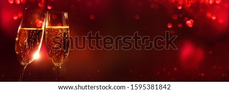 Two champagne glasses in front of romantic red bokeh background for a valentines day celebration. Royalty-Free Stock Photo #1595381842