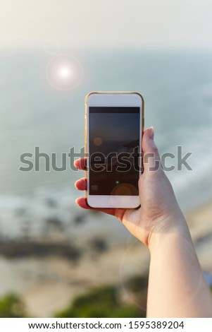 Young girl takes pictures of landscapes on the phone. The Girl photographs the sunset on the phone.  Text copy.
