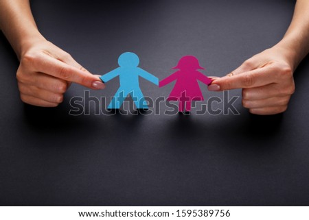 Paper chain people with female hands on black background