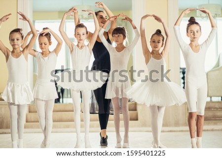 beautiful woman teach beginners ballerinas practicing classic dance in studio, a lot of little caucasian girls training with their teacher