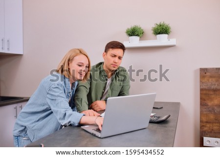 couple checking analyzing utilities bills sitting together at kitchen table, husband and beautiful wife reading bank loan documents with laptop, family managing finances planning expenses together Royalty-Free Stock Photo #1595434552