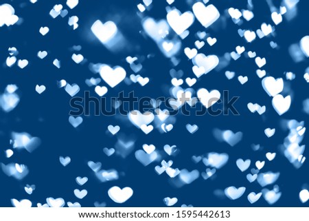 Trendy blue colored festive background with white heart bokeh. Christmas, New Year and Valentine's day design. Color trend concept 2020