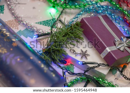 The little silver snowflake on the purple gift box with the fir branch, the colorful garland and tinsel  and blue wrapping paper. Christmas and New year background