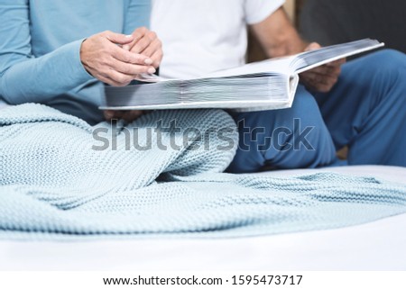 Cropped picture of an older couple hands holding an album of memories