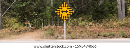 Yellow double arrow traffic sign at the end of a road with a forest. Canada
