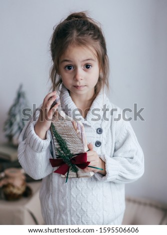 Stock Photo -  Beautiful little girl with wooden christmas decor