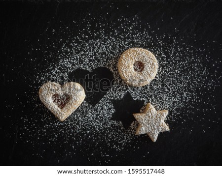 Homemade Linzer Christmas cookies. Biscuits with shortcrust pastry and strawberry jam on dark background.