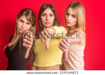 Stock photo of three girls making the no ok sign with their thumb with focus on hands.