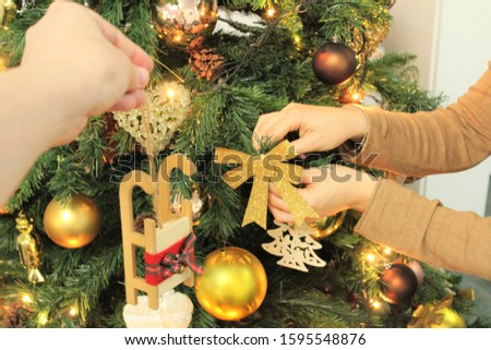 Hands are decorating christmas tree.