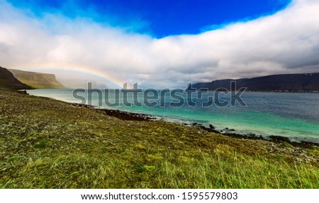 Amazing summer landscape with blue sea, white clouds and rainbow. Iceland, Europe