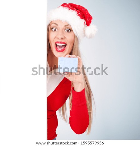Young woman holding small gift box and hiding behind white board