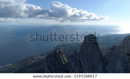 Aerial of steep mountains and funicular with people standing on the edge. Shot. Breathtaking seascape with rocks and blue cloudy sky on the background.