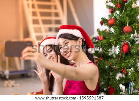 Asian womens wear a red hat and take pictures with a smartphone on Christmas.