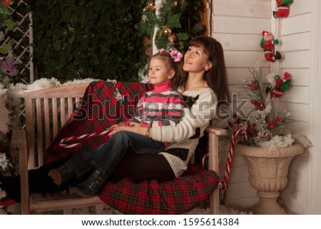 mother and daughter sitting on a swing with Christmas decor	

