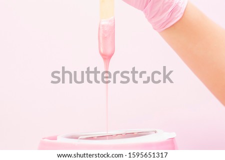 liquid wax for pink depilation drains from the stick. The concept of depilation, waxing, smooth skin without hair. Royalty-Free Stock Photo #1595651317