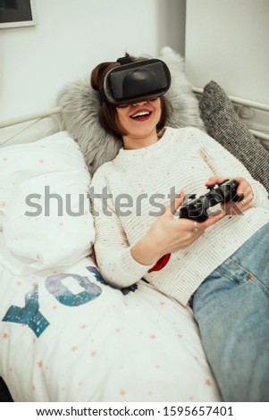 Virtual reality games. Cheerful female play video game with VR headset and joystick