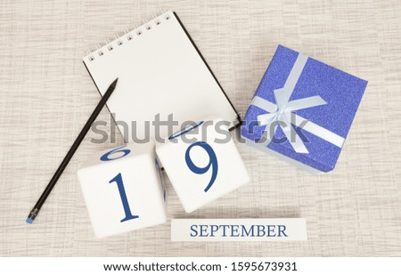 Gift box and wooden calendar with trendy blue numbers, September 19, business planner