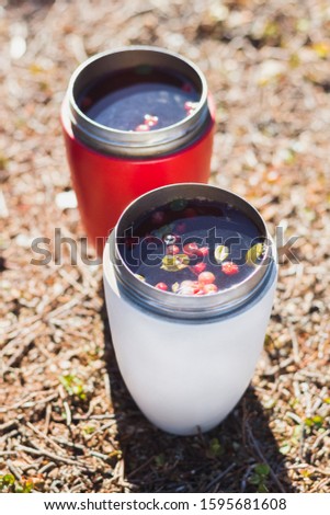 Thermo mugs with herbal and berry tea. Mountain break lunch, healthy drink. Close up picture with selective focus