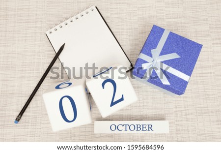 Wooden calendar for October 2, gift box in classic blue with a white ribbon, trend color numbers