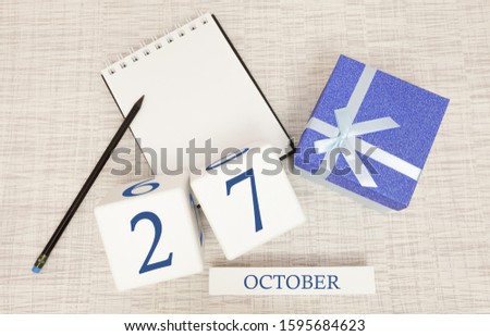 Wooden calendar for October 27, gift box in classic blue with a white ribbon, trend color numbers
