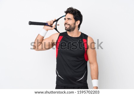 Young handsome man with beard over isolated white background playing tennis and looking up