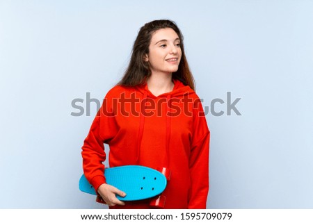 Young brunette girl over isolated blue background with skate