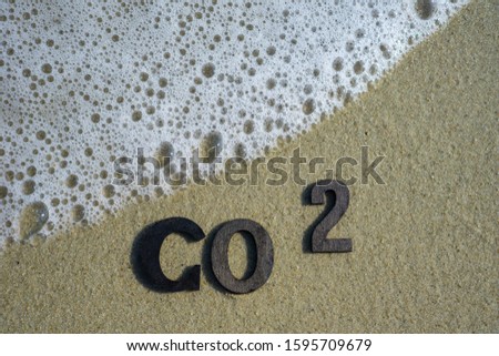 co 2 written on the beach next to a wave