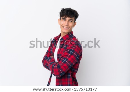 Young Argentinian man over isolated white background with arms crossed and happy