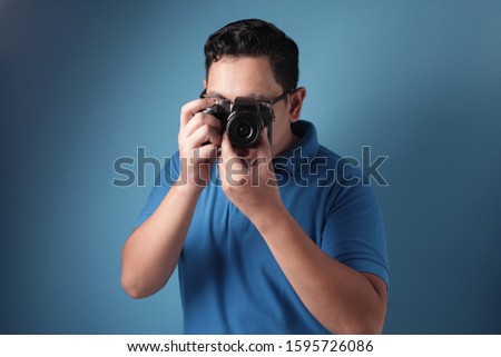 Portrait of funny young Asian man taking picture, shoot with his camera, casual photographer in action