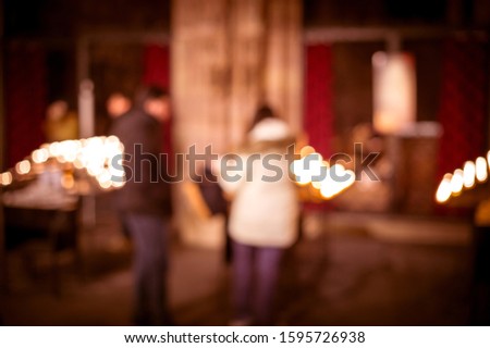 Defocused silhouettes of people in front of lighten candles in Notre-Dame de Strasbourg cathedral