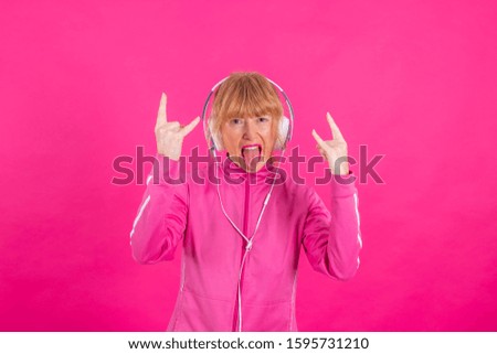 senior woman with headphones and rebel gesture isolated on color background