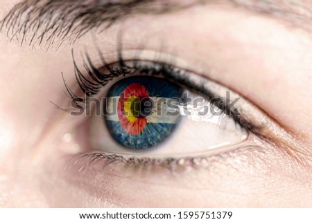 Woman green eye in close up with the flag of colorado state in iris, united states of america 