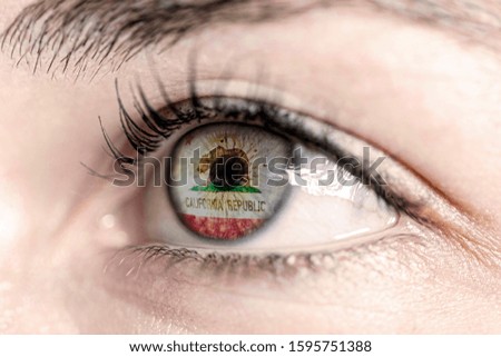 Woman green eye in close up with the flag of california state in iris, united states of america 