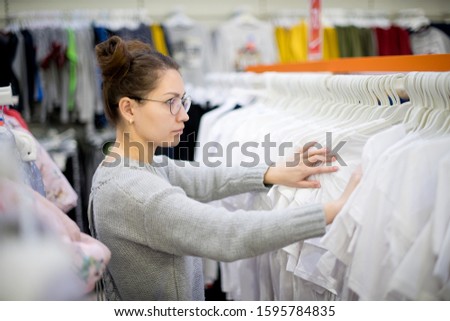 girl looking for the right size t-shirt in a row of clothes, selective focus