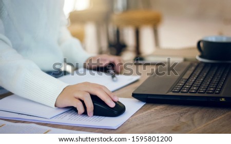 Young female hand holding computer mouse working on desk