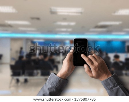 Hand holding white mobile phone with blank white screen  in bank.