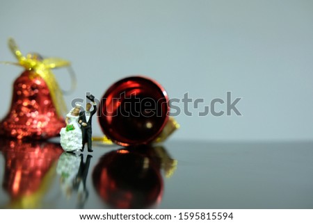 Miniature wedding concept - bride and groom walking on shiny floor with bell ornament