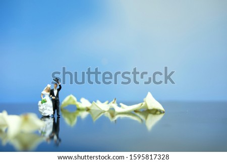Miniature photography - outdoor marriage wedding concept, bride and groom walking on white rose flower pile 