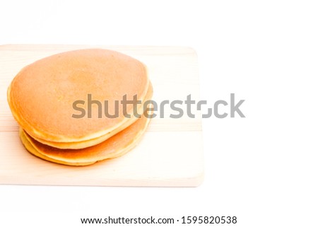 A picture of dorayaki, two small pancake-like patties made from castella wrapped around a filling of sweet azuki bean paste on wooden board.