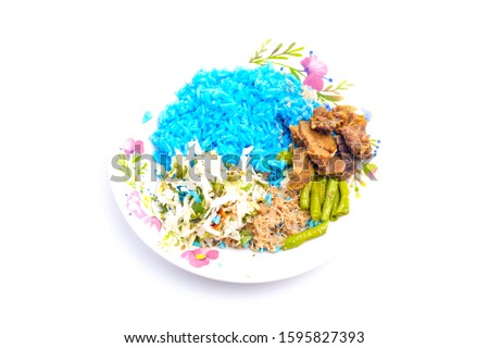 A picture of "nasi kerabu daging bakar" set on white background.Blue-coloured rice from petals of clitoria ternatea flowers ate with Malay salad and meat.  