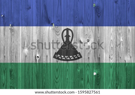 Lesotho flag depicted in bright paint colors on old wooden wall. Textured banner on rough background