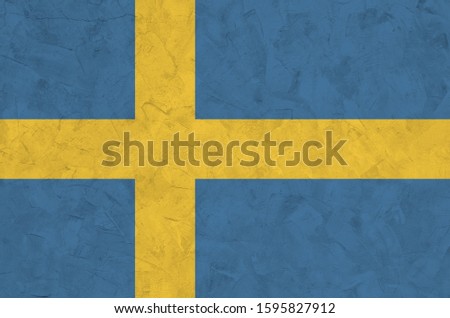 Sweden flag depicted in bright paint colors on old relief plastering wall. Textured banner on rough background