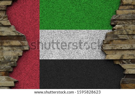 United Arab Emirates flag depicted in paint colors on old stone wall closeup. Textured banner on rock wall background