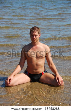 Young man in yoga pose lotus in the sea