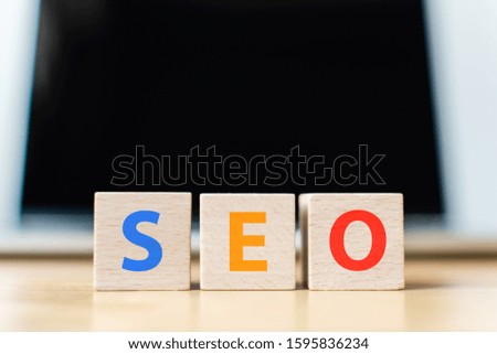 Search engine optimization concept. Wooden block cube shape with word SEO and laptop