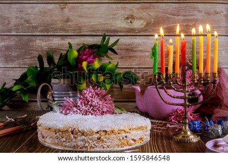 Hanukkah sweet pie with burning colored candles on menorah. Jewish holiday concept.