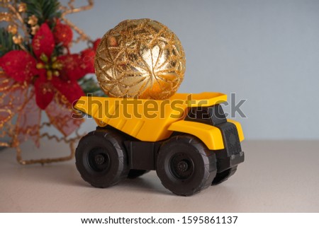 Yellow dump truck model with Christmas tree toy. Garland lights in defocus