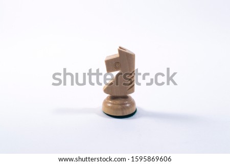 A chess piece is a white knight. Wooden varnished chess piece on a white background.