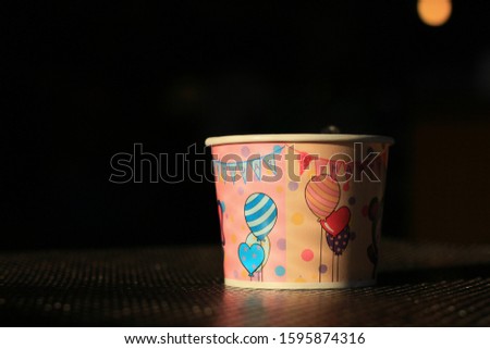 Cute cartoon paper cups on black metal sheet table background