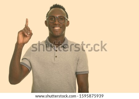 Young happy black African man smiling while pointing finger up